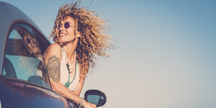 Une femme sortant son buste par la fenêtre passager les cheveux au vent